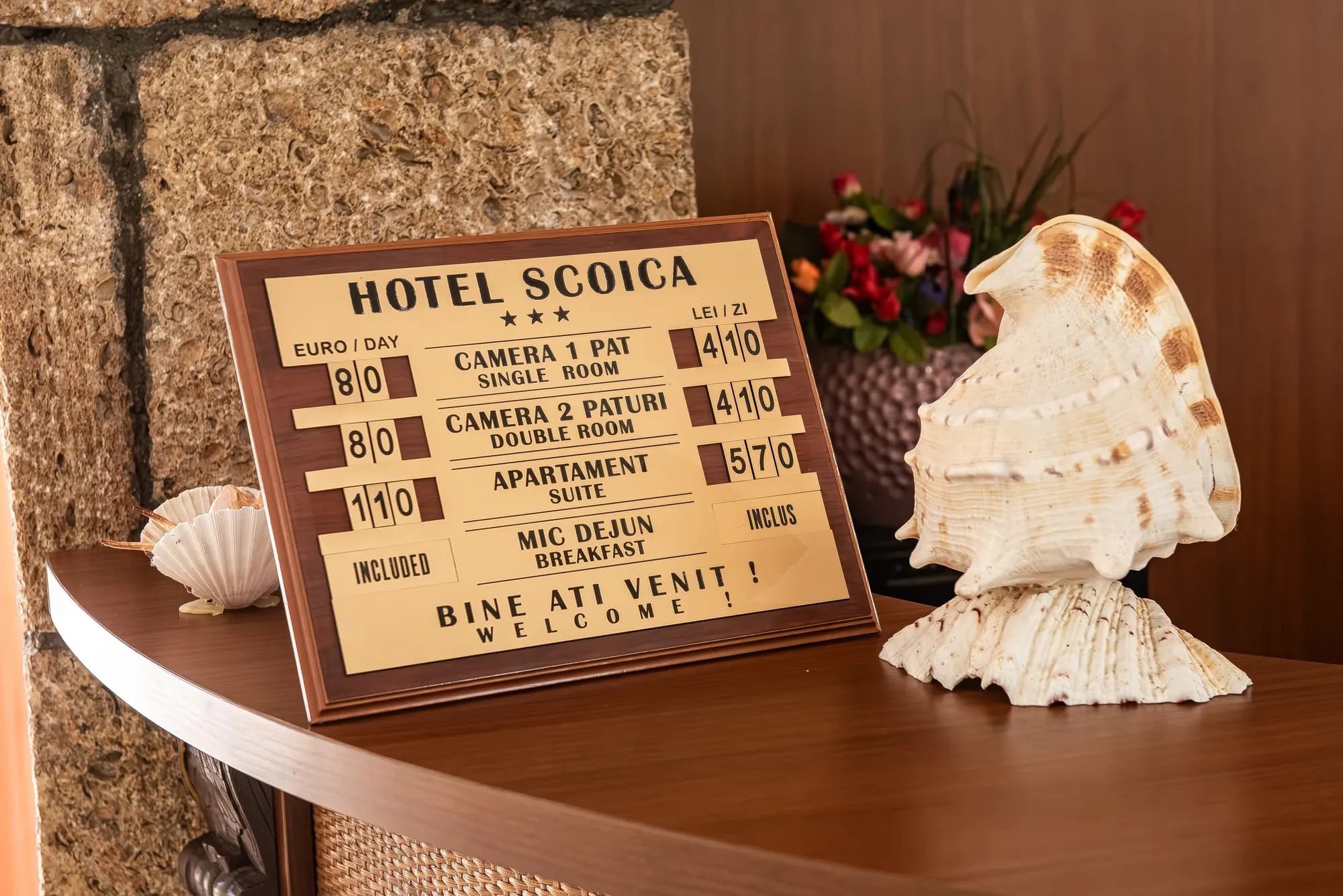 Panoul cu tarife Hotel Scoica, decorat cu scoici și flori