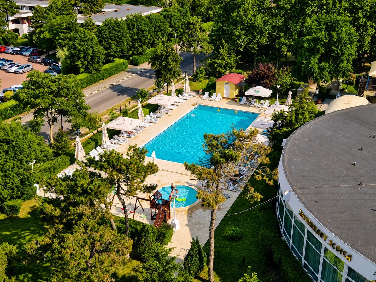 Vedere aeriană asupra piscinelor, locului de joacă și restaurantului