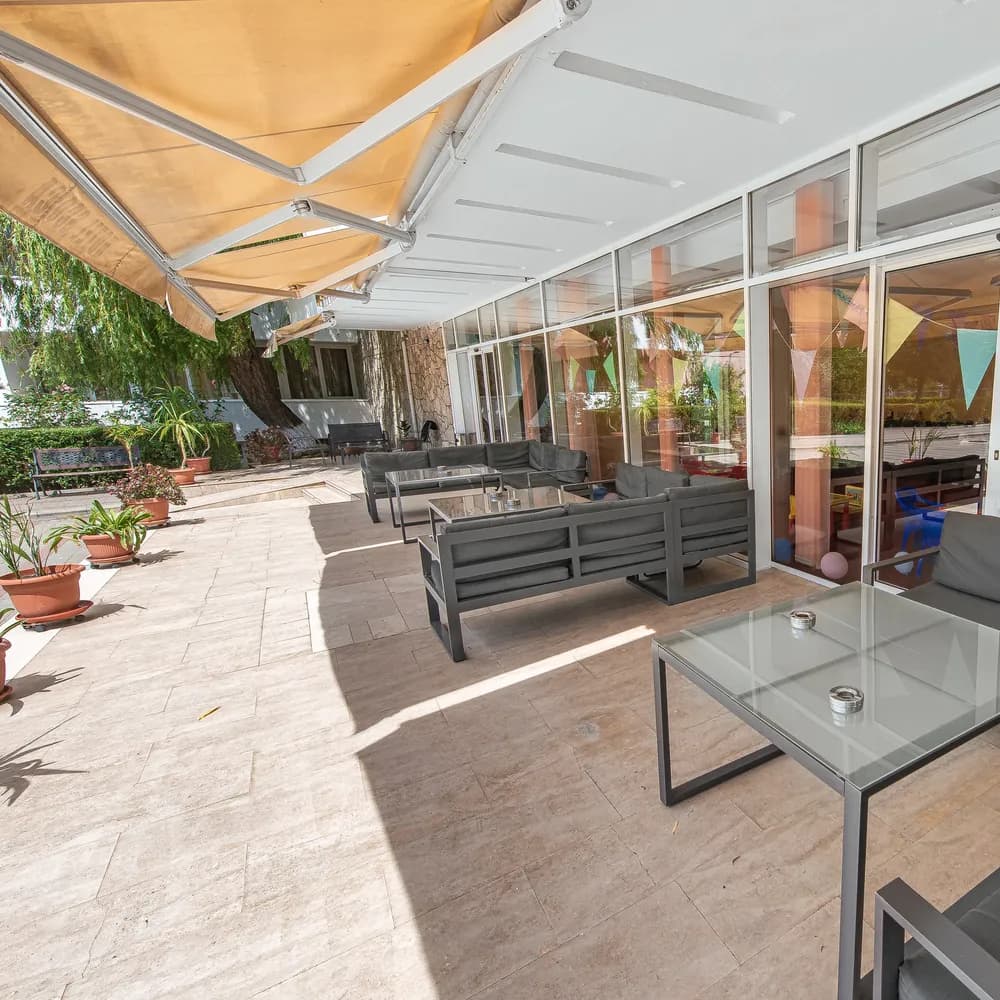 Terasa-lounge acoperită, cu mobilier confortabil și vedere spre grădină